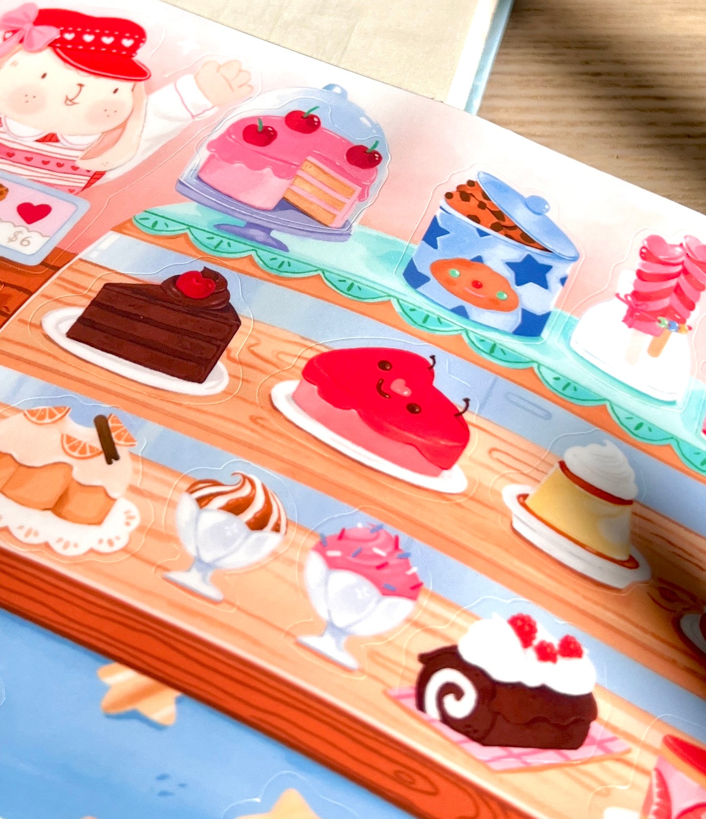 Colorful sticker sheet with illustrations of desserts on a wooden surface.