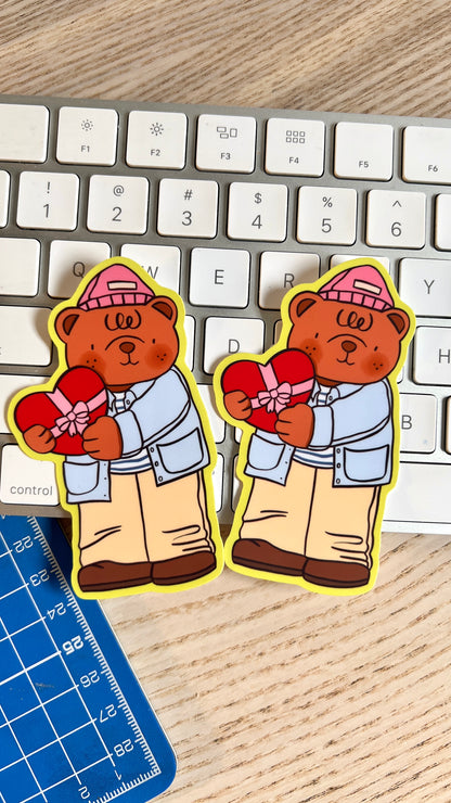 Two stickers of a bear holding a heart on a keyboard with a ruler below.