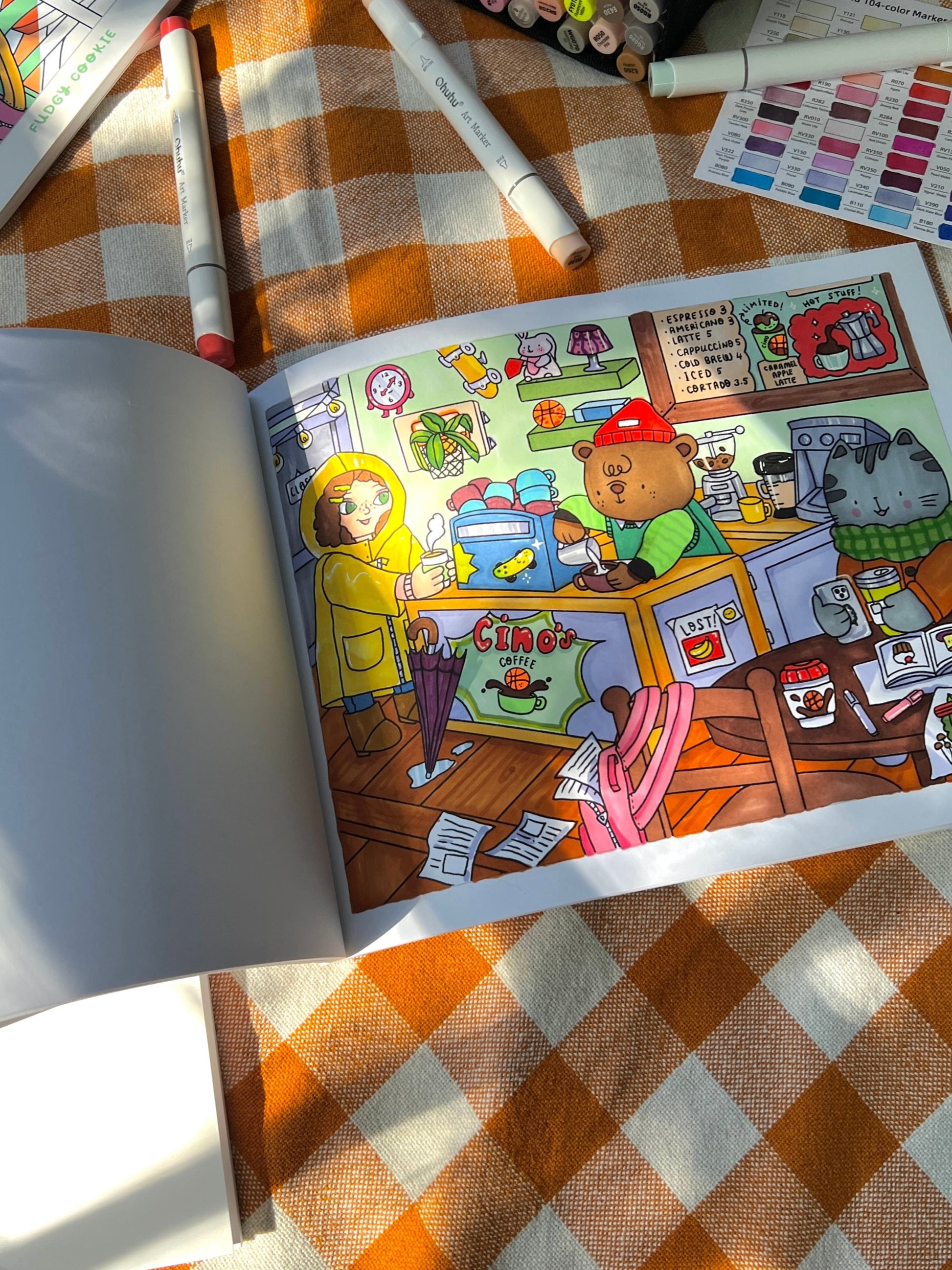 Open coloring book with colorful illustrations on a checkered tablecloth